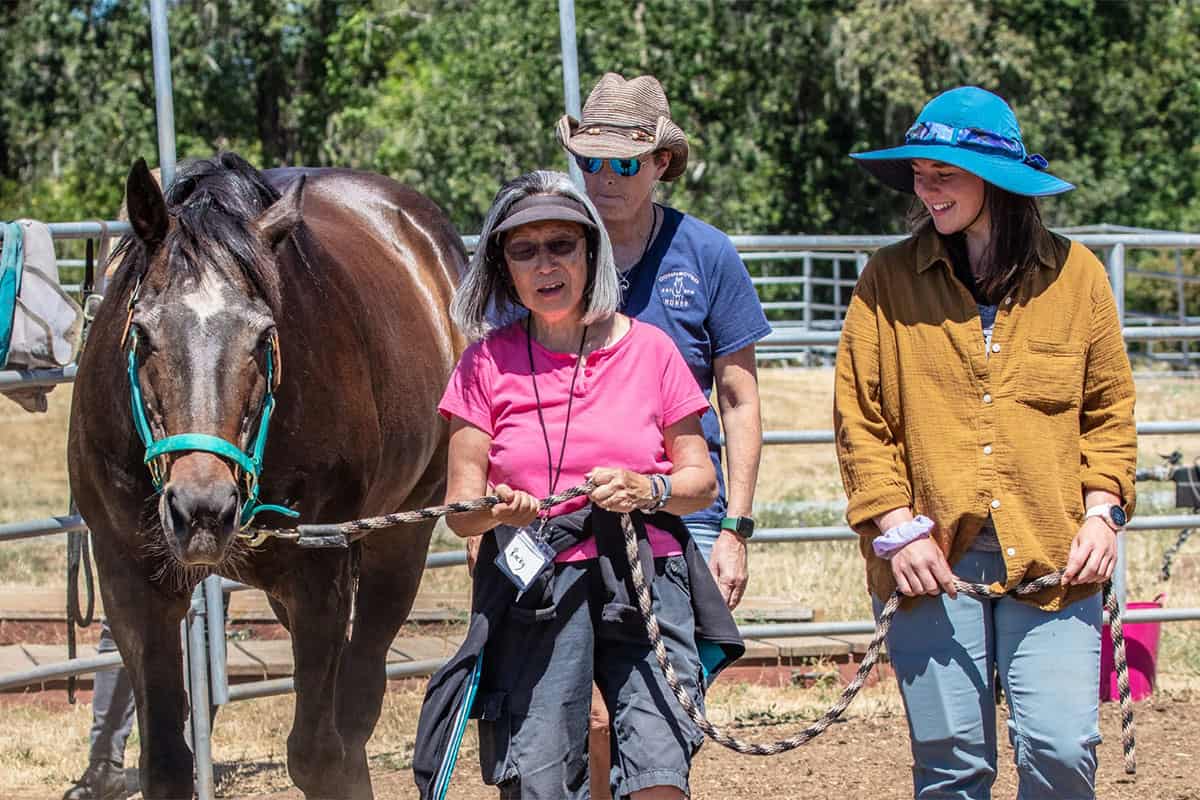 three people walking with a horse