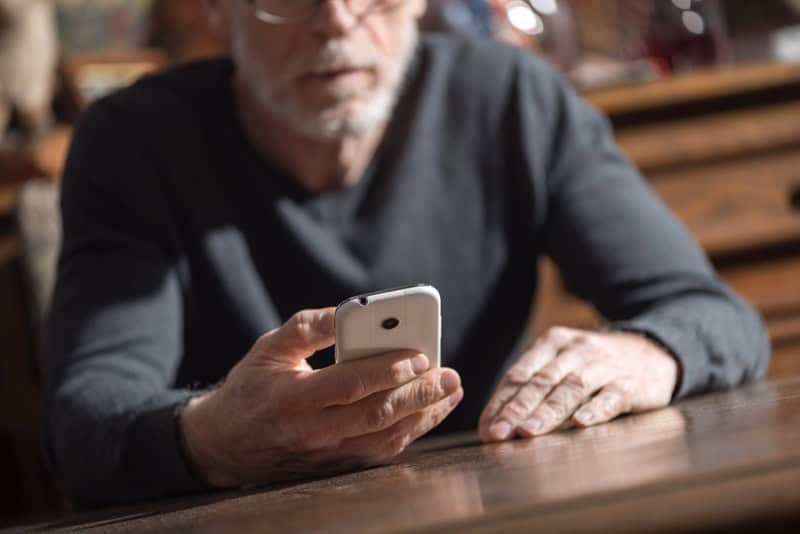 Senior man using his phone at home, hard light effect